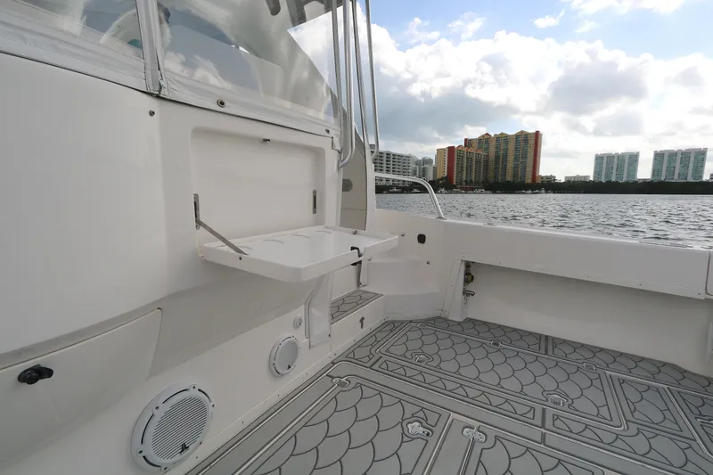 Slide: The Image of 2012 Intrepid 475 Sport Yacht deck with foldable table, overlooking waterfront cityscape. - 14