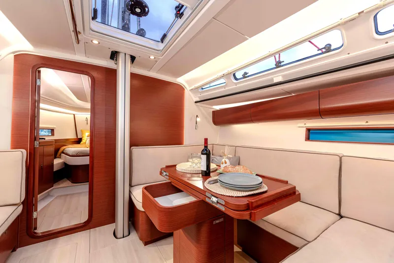 Slide: The Image of 2026 Dehler 46 yacht sailing near a scenic coastline with lush greenery and a historic building. - 36