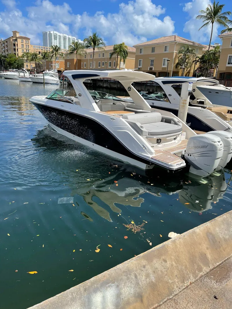 Slide: The Image of 2021 Sea Ray SLX 310 OB luxury motorboat docked in a sunny marina. - 1