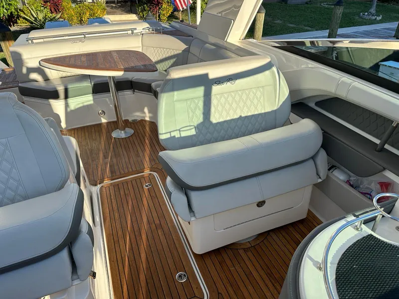 Slide: The Image of 2021 Sea Ray SLX 310 OB boat interior with teak flooring and cushioned seating. - 17