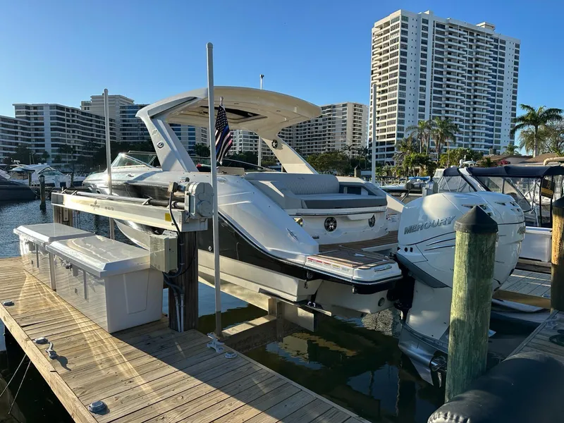 Slide: The Image of 2021 Sea Ray SLX 310 OB docked at a marina with high-rise buildings in the background. - 2