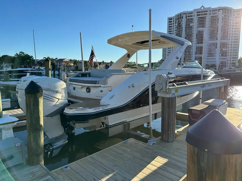Slide: The Image of 2021 Sea Ray SLX 310 OB docked at a marina with a cityscape background. - 3
