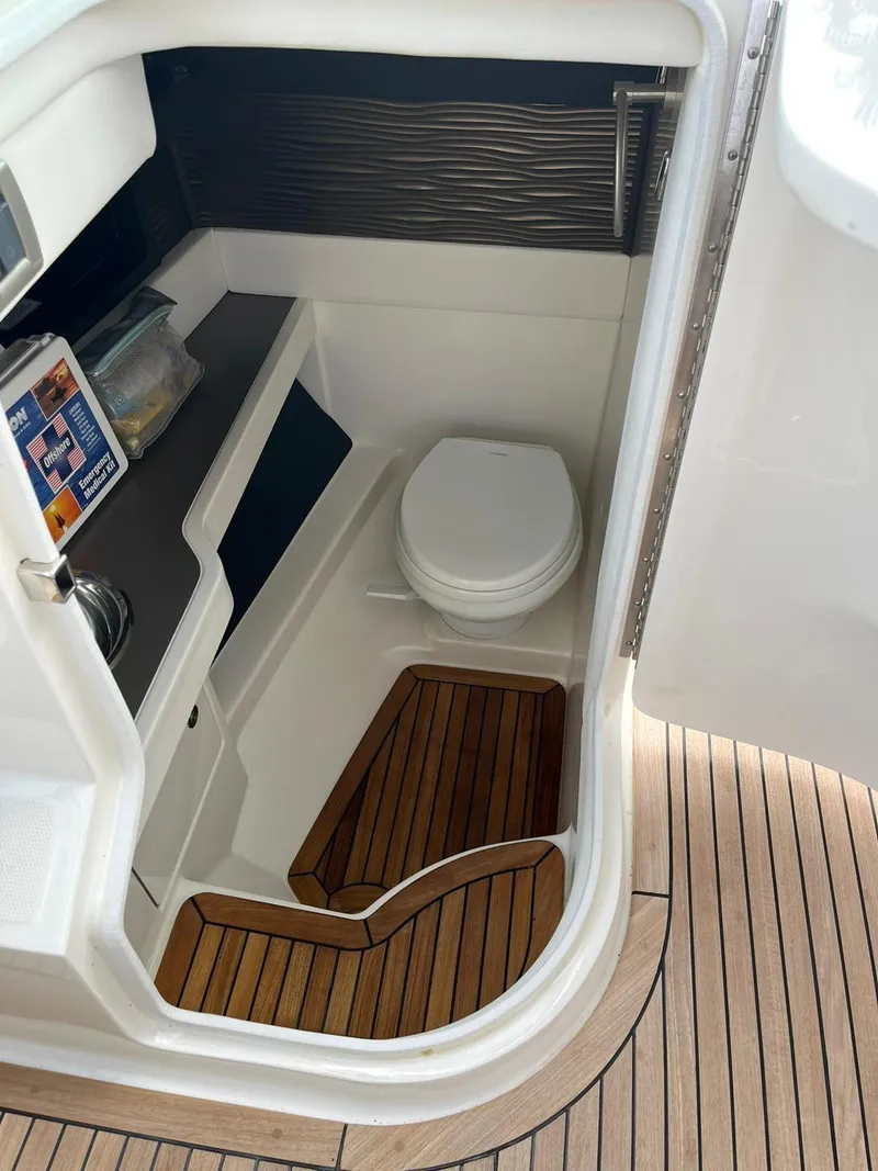 Slide: The Image of 2021 Sea Ray SLX 310 OB boat interior with toilet and wooden flooring. - 9