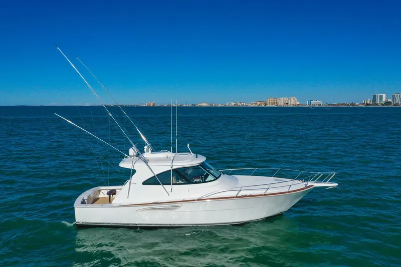 Slide: The Image of 2022 Viking 44 Sport Coupe yacht cruising on open water under clear blue skies. - 1