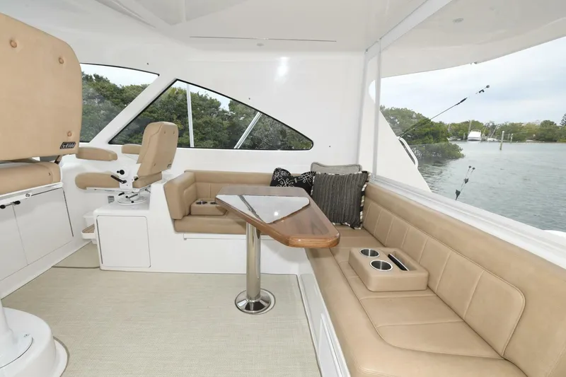 Slide: The Image of 2022 Viking 44 Sport Coupe interior with beige seating and table, overlooking water. - 10