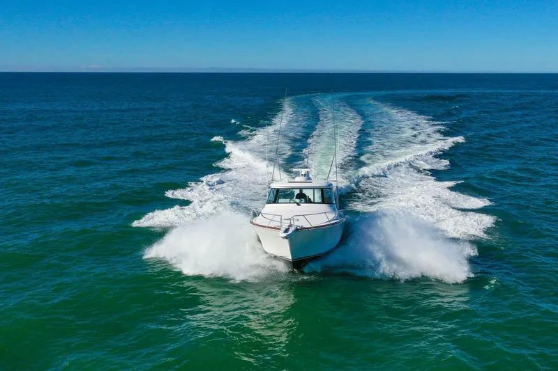 Slide: The Image of 2022 Viking 44 Sport Coupe cruising on open ocean, leaving a wake behind. - 22