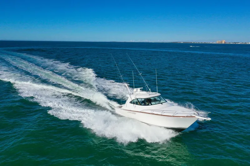 Slide: The Image of 2022 Viking 44 Sport Coupe cruising on open water under clear blue skies. - 23