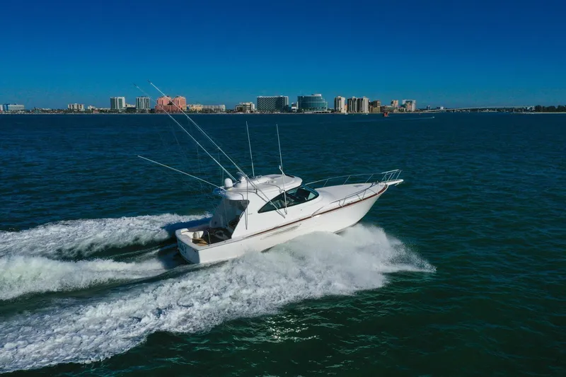 Slide: The Image of 2022 Viking 44 Sport Coupe cruising on open water with city skyline in background. - 34