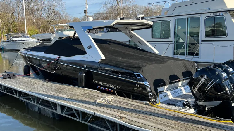 Slide: The Image of 2021 Monterey 385 SE boat docked with black cover and Mercury engines. - 2
