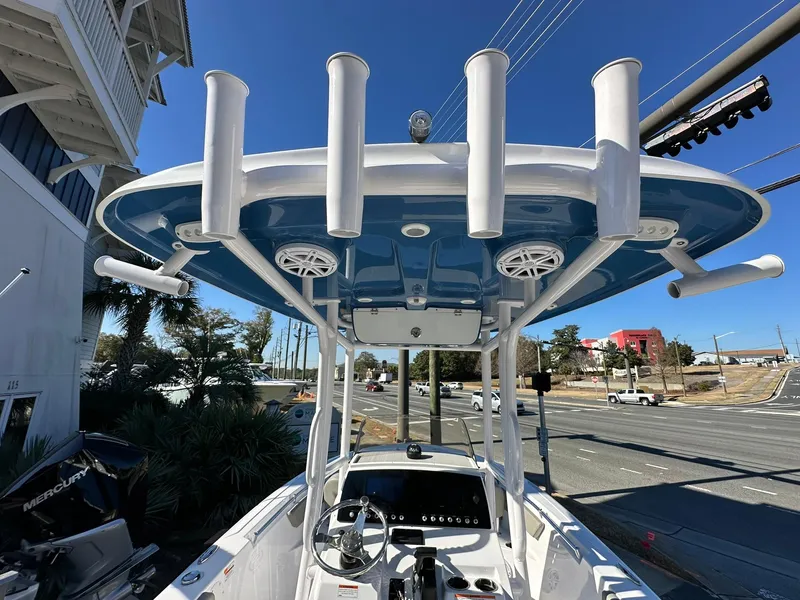 Slide: The Image of 2023 Sportsman Open 212 Center Console boat with T-top and rod holders, docked near a road. - 25