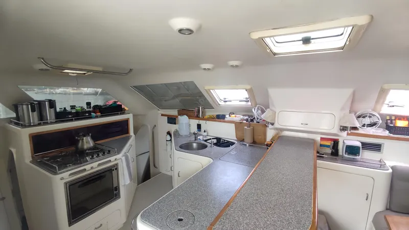 Slide: The Image of Interior of 2002 Voyage 440 catamaran kitchen with stove, sink, and ample counter space. - 14