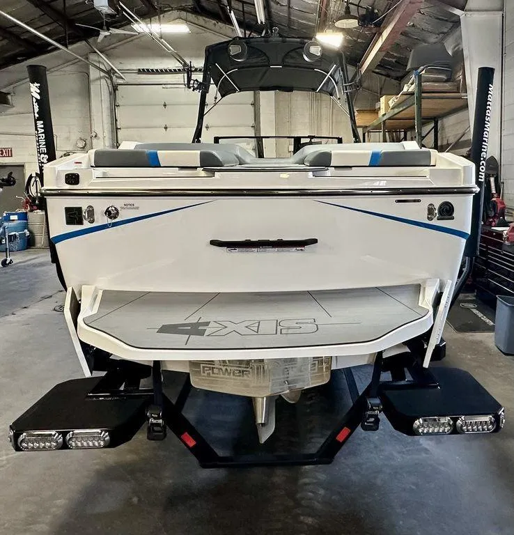 Slide: The Image of 2024 Axis T250 boat in a garage, rear view with swim platform and wakeboard racks. - 15