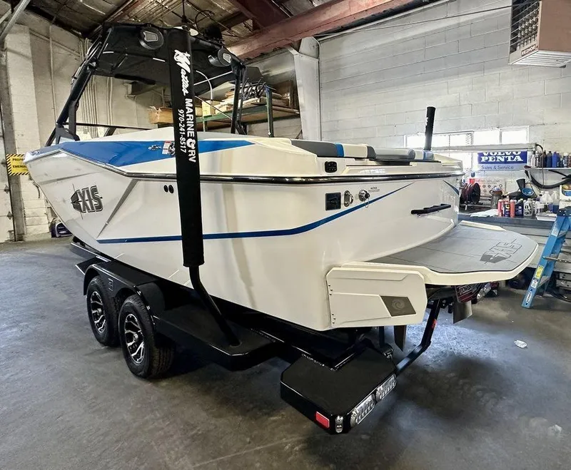 Slide: The Image of 2024 Axis T250 boat in a garage, featuring sleek design and dual-axle trailer. - 16