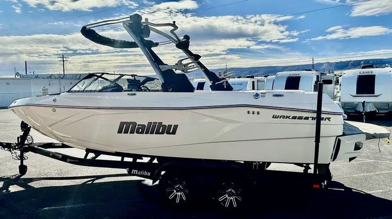 Slide: The Image of 2024 Malibu 23 LSV boat on trailer under blue sky. - 3
