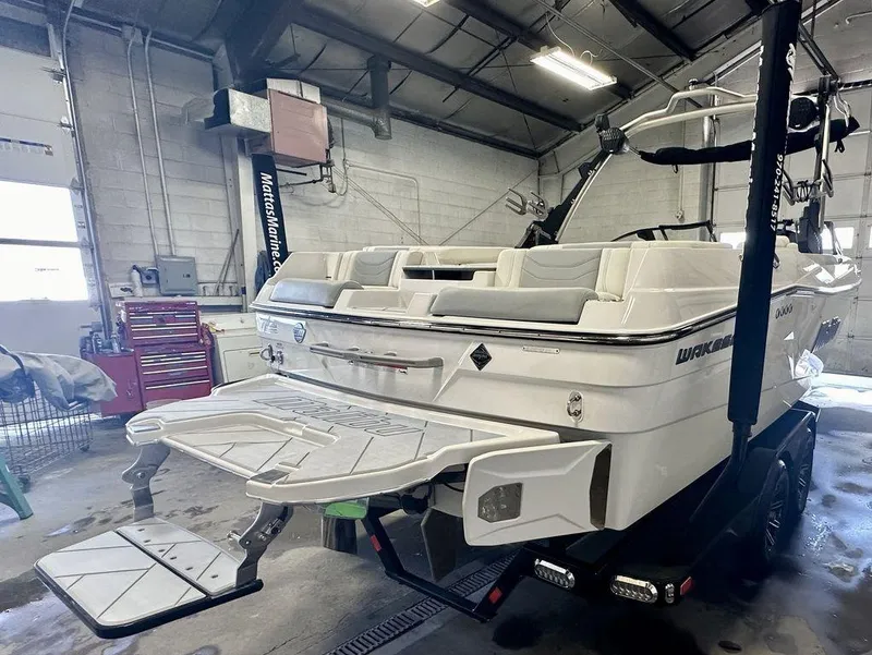 Slide: The Image of 2024 Malibu 23 LSV boat in a garage, showcasing rear deck and seating. - 6
