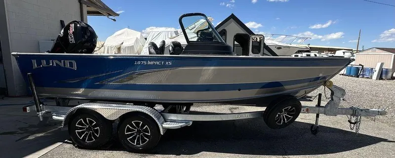 Slide: The Image of 2024 Lund 1875 Impact XS Sport boat on a trailer in a marina. - 1