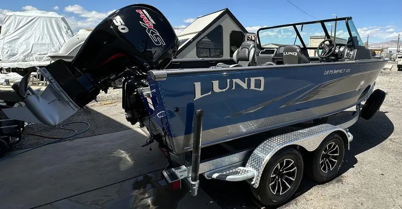 Slide: The Image of 2024 Lund 1875 Impact XS Sport boat on a trailer with a 150 HP Mercury engine. - 2
