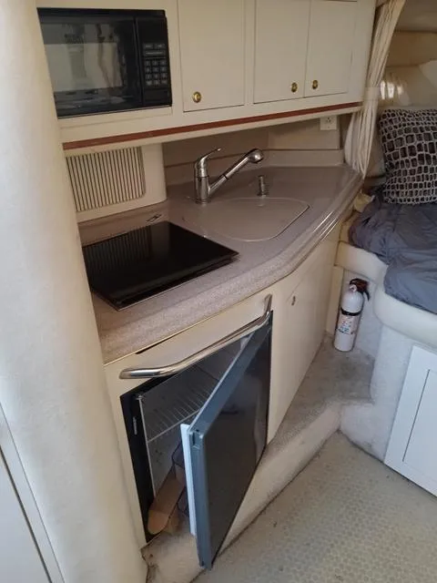 Slide: The Image of 2001 Sea Ray 290 Amberjack cabin kitchen with sink, stove, microwave, and mini-fridge. - 9