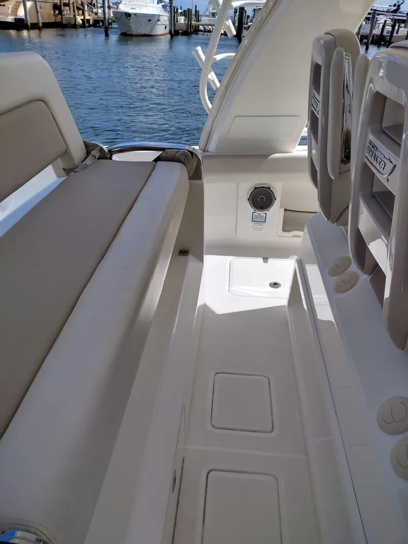 Slide: The Image of 2018 Boston Whaler 420 Outrage interior with seating and storage, docked by the water. - 21