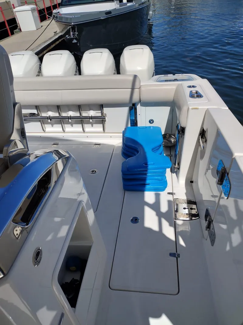 Slide: The Image of 2018 Boston Whaler 420 Outrage boat deck with seating and storage, docked by the water. - 22