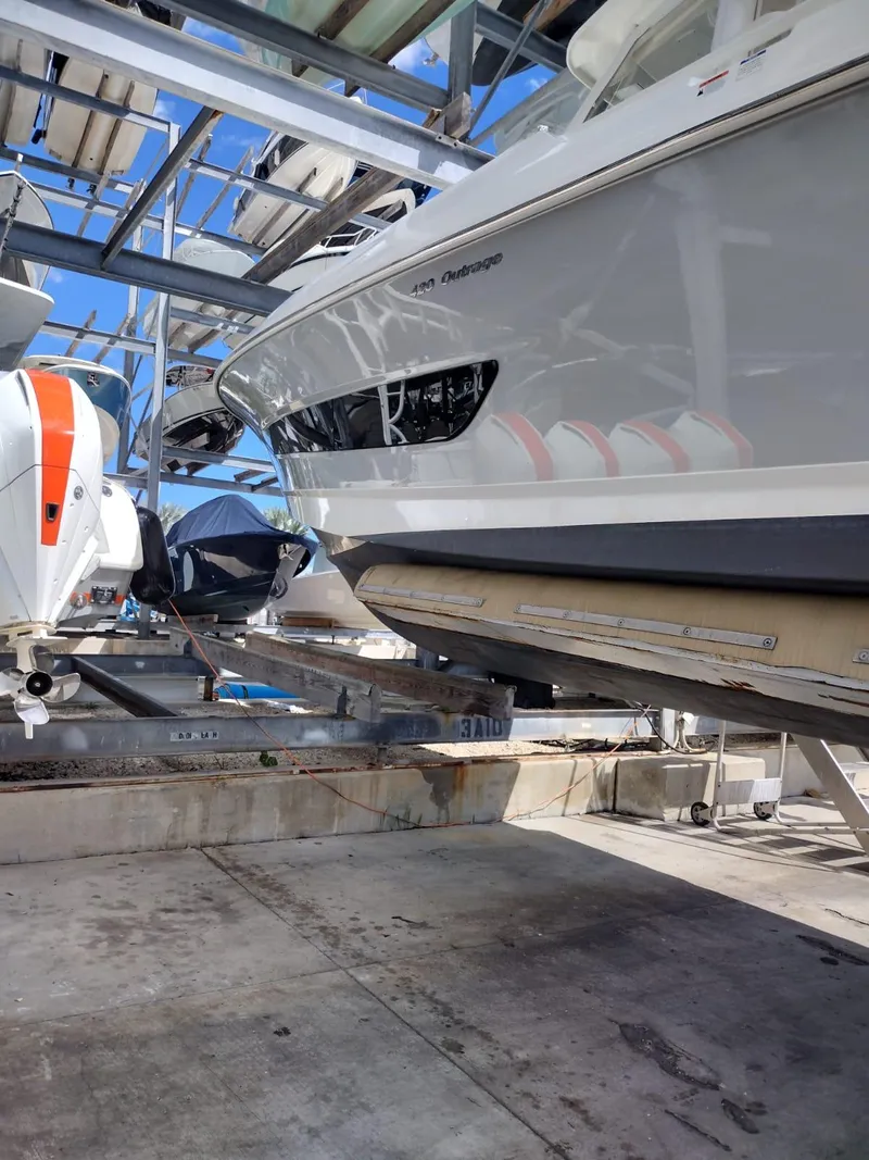 Slide: The Image of 2018 Boston Whaler 420 Outrage boat in storage, side view with visible hull and engines. - 26