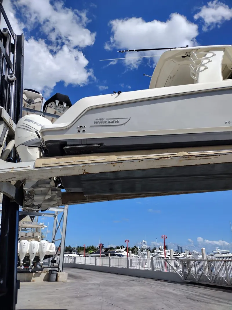 Slide: The Image of 2018 Boston Whaler 420 Outrage on lift, clear sky, marina background. - 27