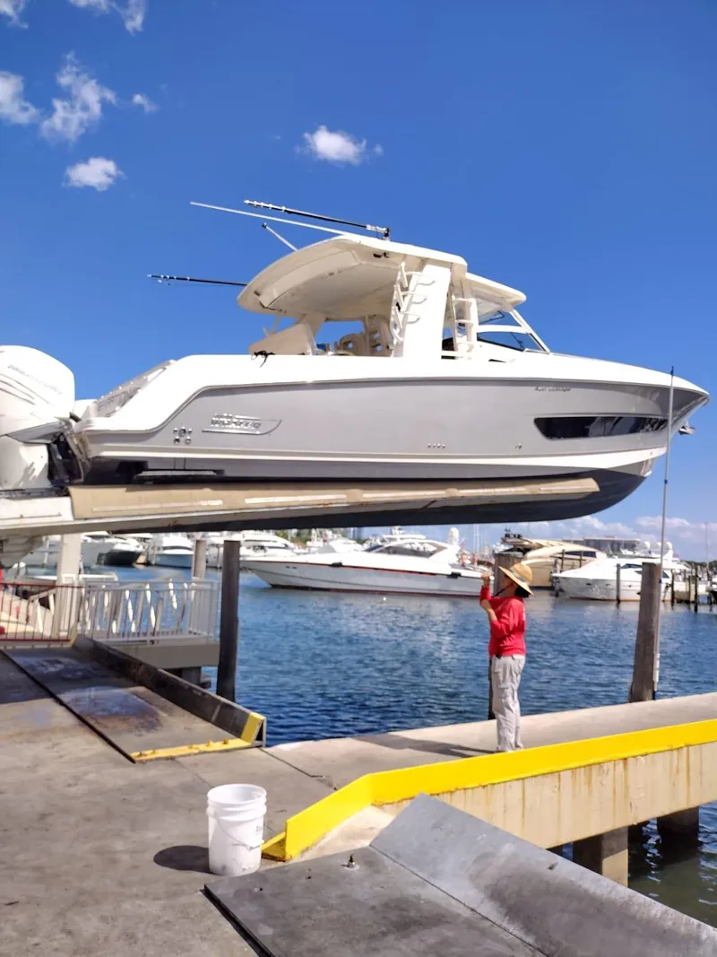 Slide: The Image of 2018 Boston Whaler 420 Outrage being lifted at a marina under a clear blue sky. - 31