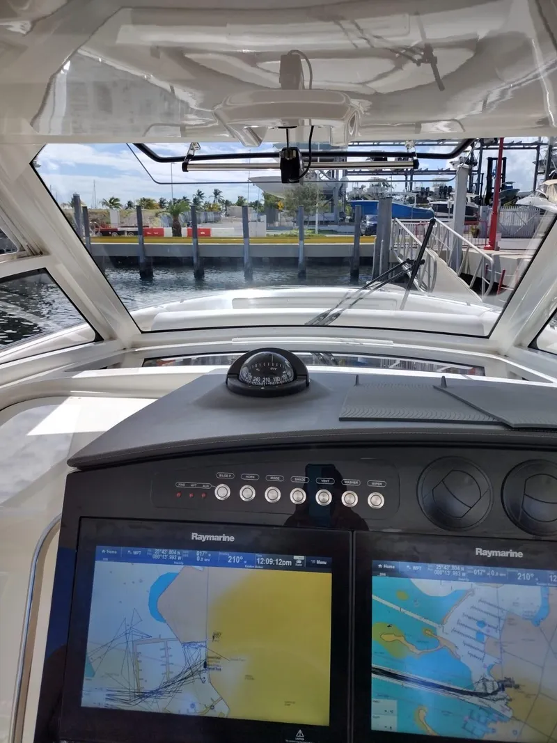 Slide: The Image of 2018 Boston Whaler 420 Outrage helm with navigation screens and compass, docked at marina. - 42
