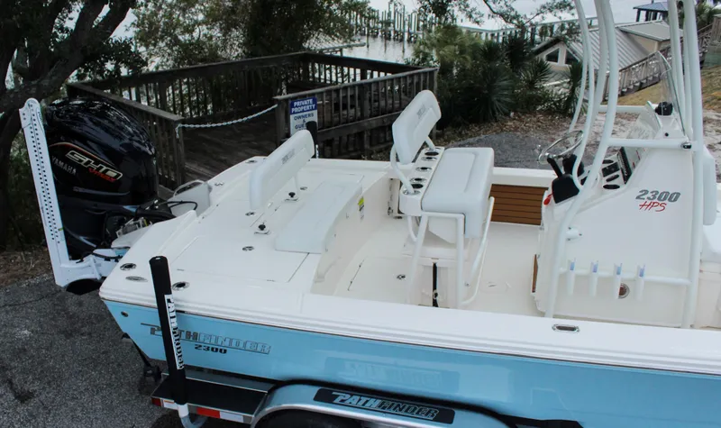 Slide: The Image of 2024 Pathfinder 2300 HPS boat with seating and motor, docked on a trailer. - 8