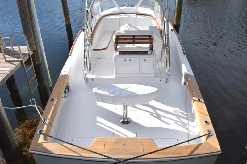 Slide: The Image of 2024 L&H Walk-Around Sportfish boat docked, featuring spacious deck and seating area. - 2