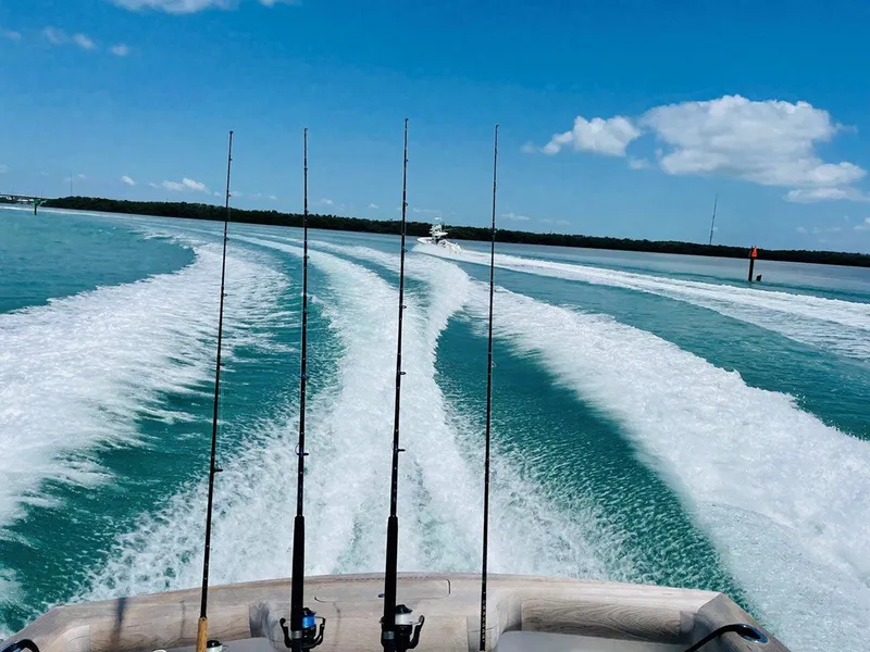 Slide: The Image of 2024 L&H Walk-Around Sportfish boat cruising on clear blue waters with fishing rods. - 37