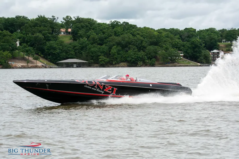 The Image of 2009 Donzi 38 ZRC speedboat cruising on a lake with lush green trees in the background. - 0
