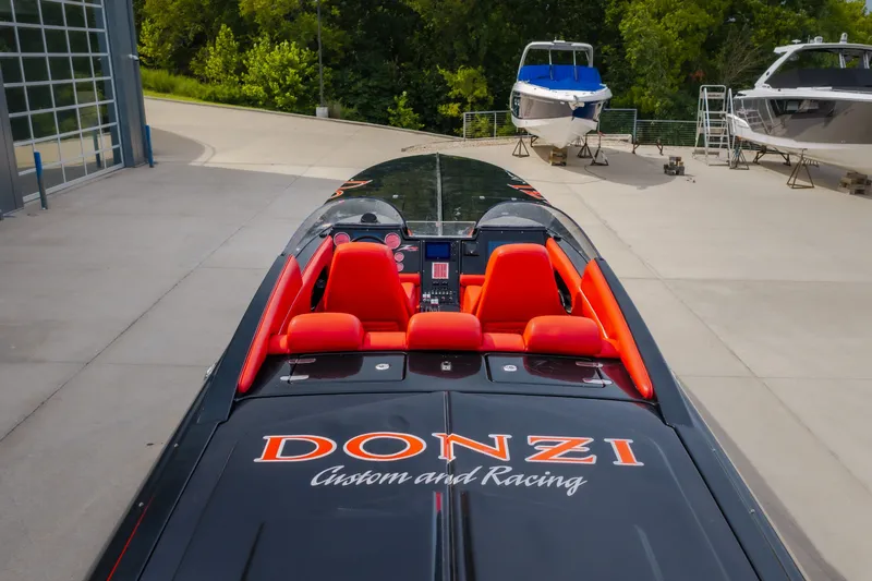 Slide: The Image of 2009 Donzi 38 ZRC speedboat with vibrant red seats, parked near other boats. - 33