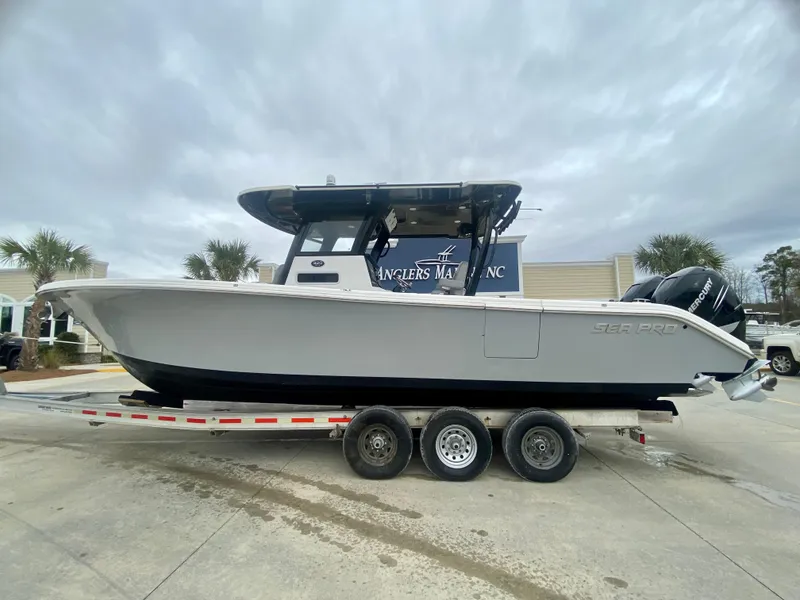 Slide: The Image of 2022 Sea Pro 320 DXL boat on a triple-axle trailer at a marina. - 0
