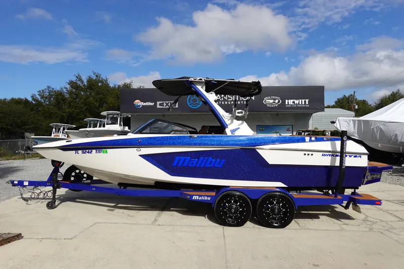 The Image of 2023 Malibu Wakesetter 24 MXZ boat on trailer, blue and white, side view. - 0