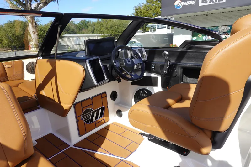 Slide: The Image of 2023 Malibu Wakesetter 24 MXZ boat interior with tan seats and modern dashboard. - 10