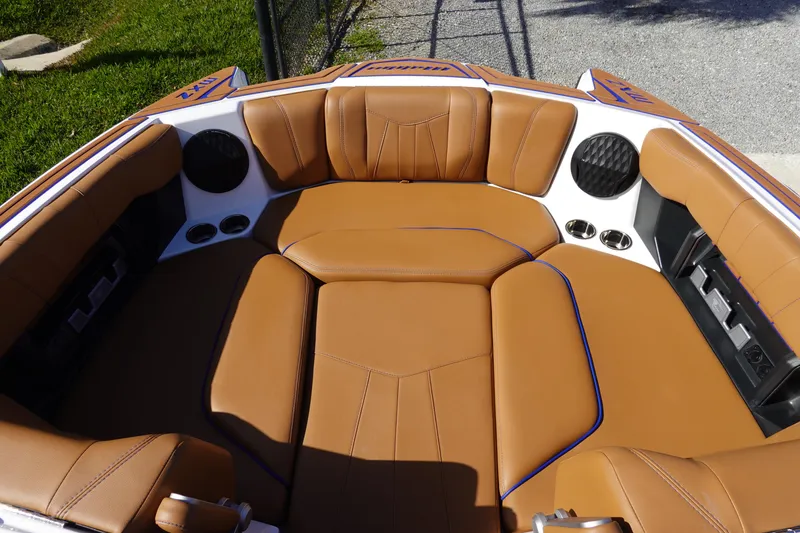 Slide: The Image of 2023 Malibu Wakesetter 24 MXZ boat interior with tan leather seating and built-in speakers. - 16