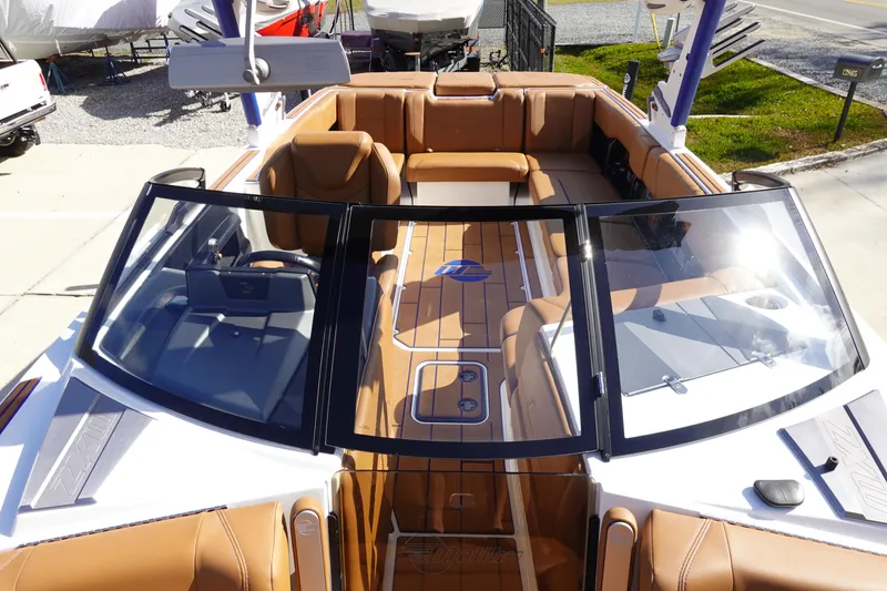 Slide: The Image of 2023 Malibu Wakesetter 24 MXZ boat interior with tan leather seating and open windshield. - 17