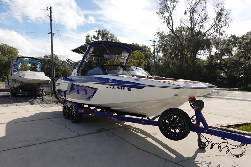 Slide: The Image of 2023 Malibu Wakesetter 24 MXZ boat on a trailer in a driveway. - 2