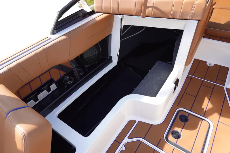 Slide: The Image of 2023 Malibu Wakesetter 24 MXZ interior storage compartment with brown seating and flooring. - 30