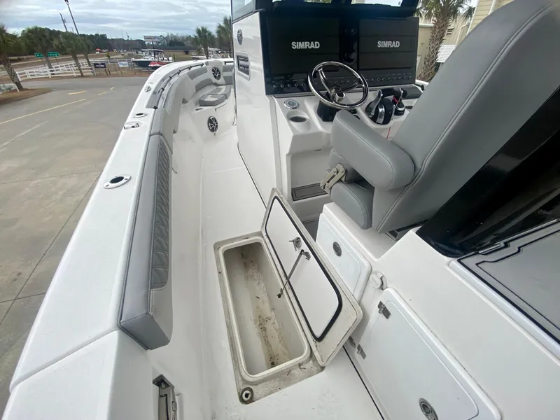 Slide: The Image of 2022 Sea Pro 320 DXL boat interior with open storage compartment and Simrad electronics. - 18