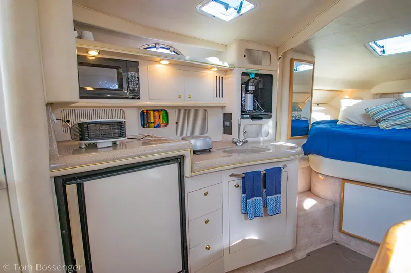 Slide: The Image of Interior of 1999 Sea Ray 340 Sundancer yacht with kitchenette and cozy sleeping area. - 11