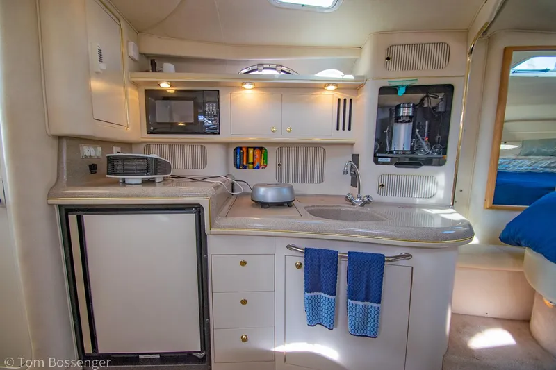 Slide: The Image of 1999 Sea Ray 340 Sundancer galley with compact kitchen, fridge, and microwave. - 13