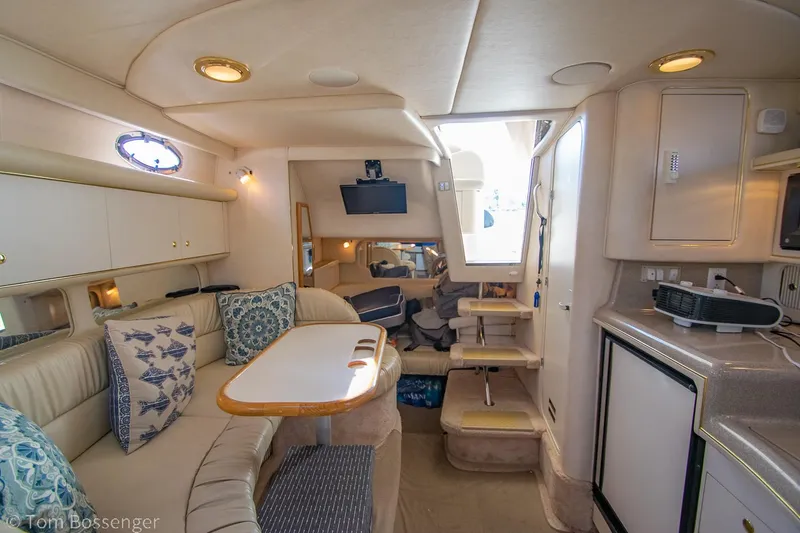 Slide: The Image of 1999 Sea Ray 340 Sundancer interior with cozy seating, table, and kitchenette. - 16