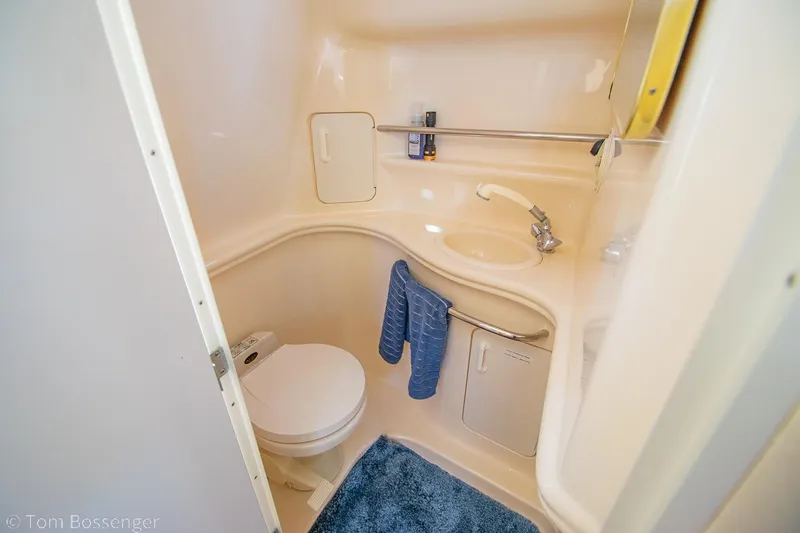 Slide: The Image of 1999 Sea Ray 340 Sundancer bathroom with toilet, sink, and blue mat. - 19