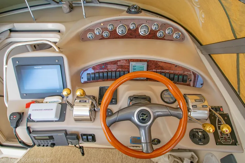 Slide: The Image of 1999 Sea Ray 340 Sundancer helm with wood steering wheel and modern controls. - 24