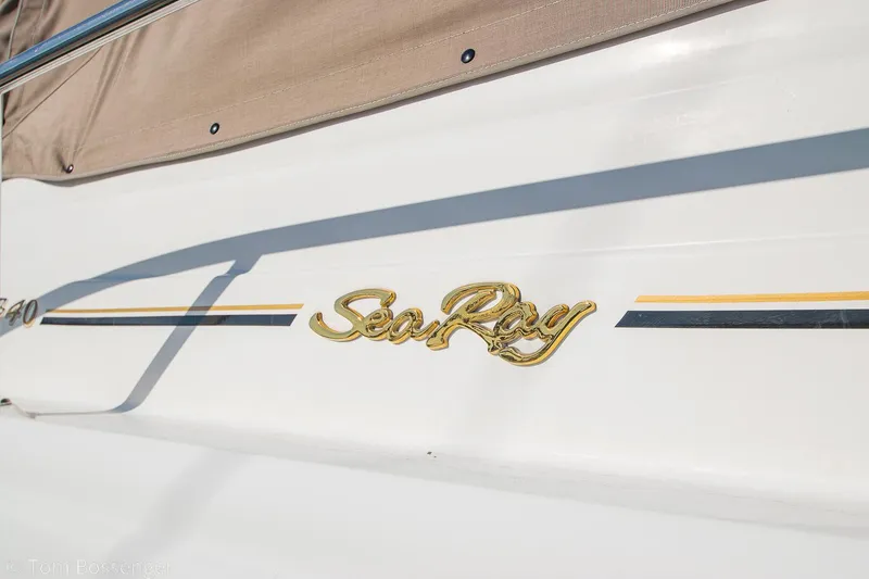 Slide: The Image of 1999 Sea Ray 340 Sundancer boat with gold logo and beige cover. - 4