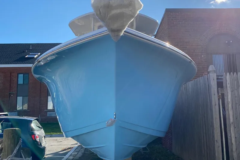 Slide: The Image of 2024 Sea Pro 242 boat in light blue, docked near a brick building. - 2