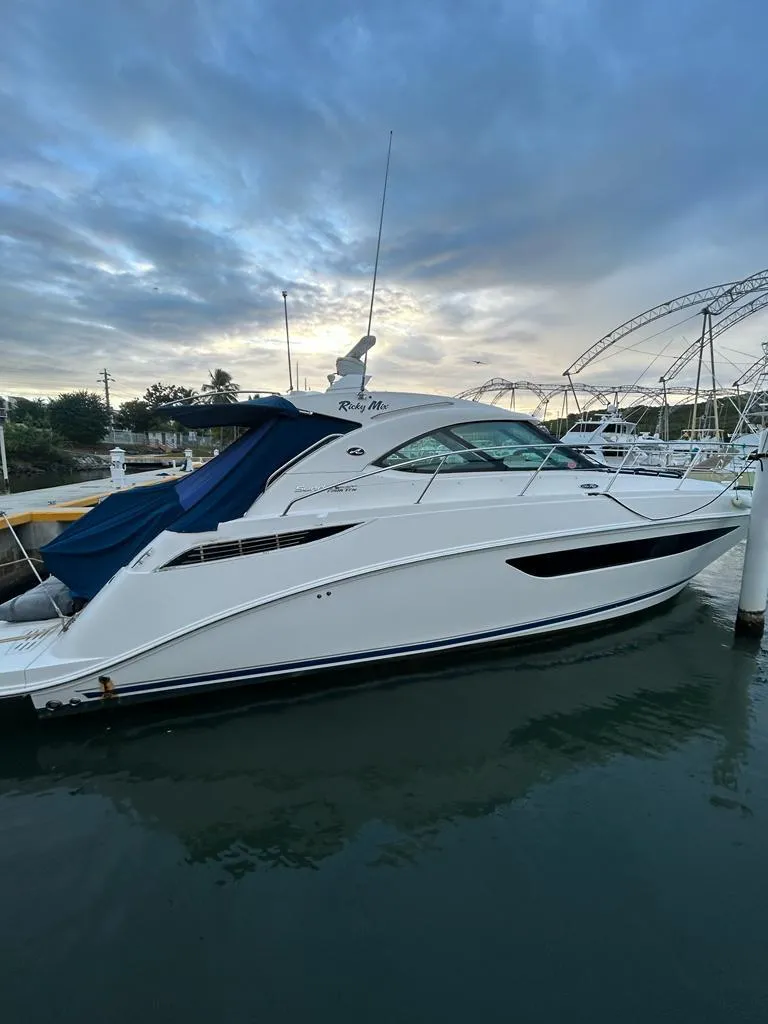 The Image of 2013 Sea Ray 410 Sundancer yacht docked at marina under cloudy sky. - 0