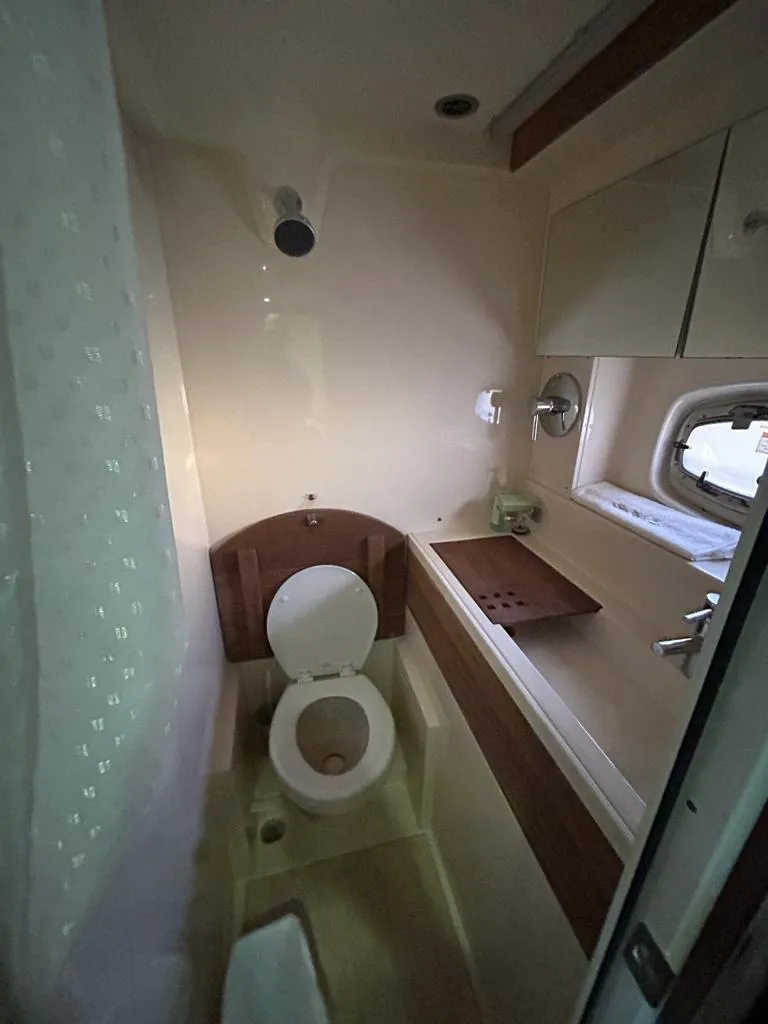 Slide: The Image of 2013 Sea Ray 410 Sundancer bathroom with toilet, sink, and window. - 12